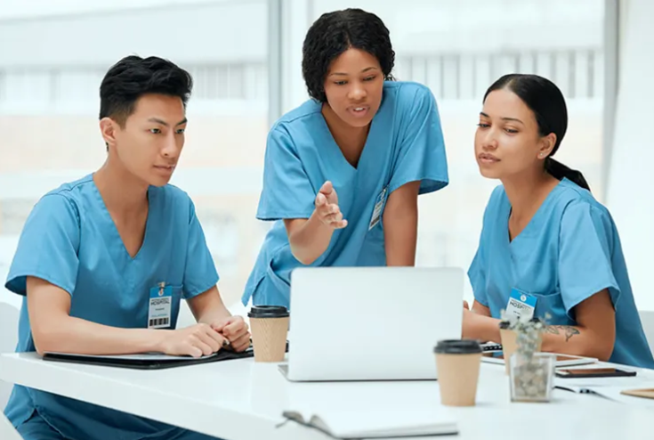 Three nurses sitting around a laptop