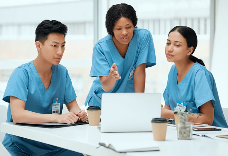 3 nurses sitting around a laptop